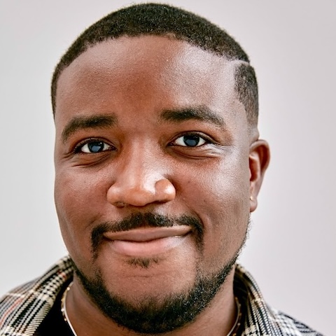 The smiling face of a man with short dark hair and beard.