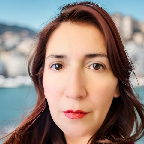 Close up of a woman's face with shoulder-length hair in front of a background of somewhere bright and sunny outside.