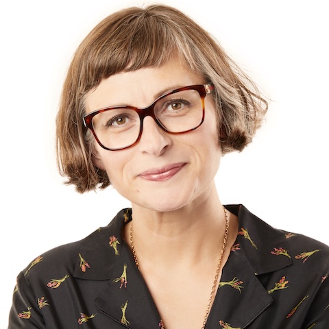 Head and shoulders shot of a woman with medium length hair and glasses in front of a white background.